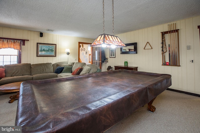 playroom with carpet floors, a textured ceiling, visible vents, and wood walls