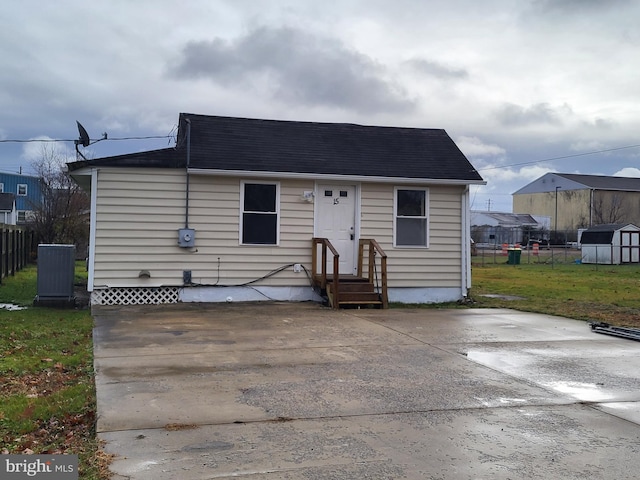 view of front of house featuring an outdoor structure, fence, a shed, and a front yard