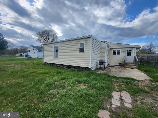 rear view of property with fence, a patio area, a lawn, and entry steps