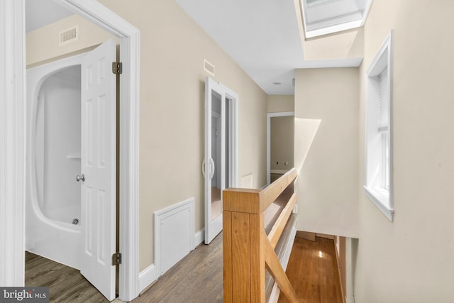 hallway featuring an upstairs landing, wood finished floors, visible vents, and baseboards