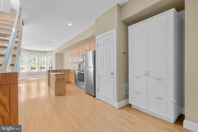 kitchen featuring light wood finished floors, visible vents, appliances with stainless steel finishes, and baseboards