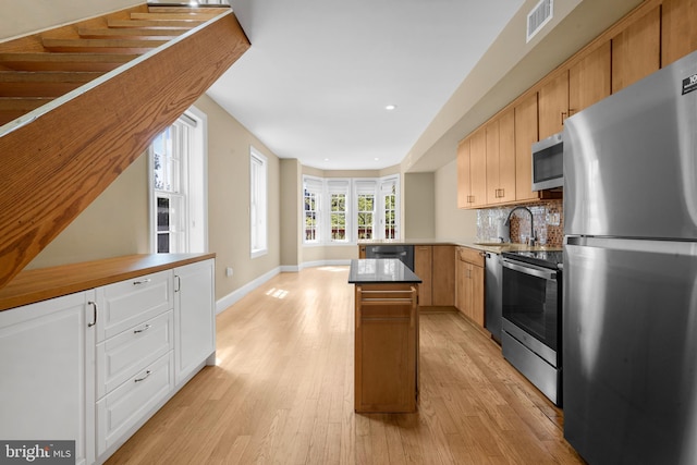 kitchen featuring appliances with stainless steel finishes, visible vents, a peninsula, and light wood-type flooring