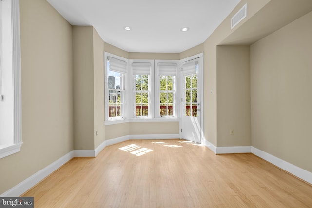 empty room with visible vents, light wood-type flooring, and baseboards