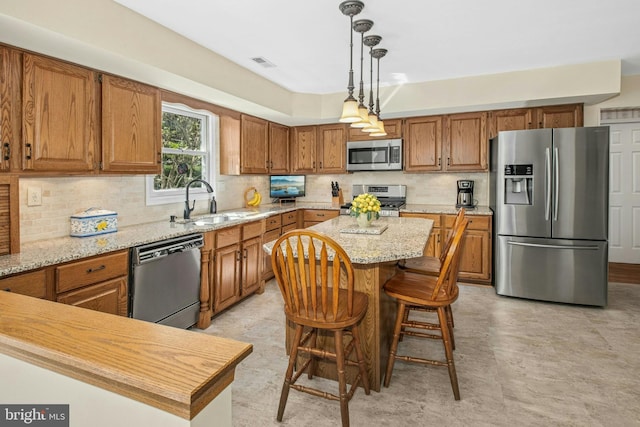 kitchen featuring visible vents, a center island, brown cabinets, a sink, and stainless steel appliances