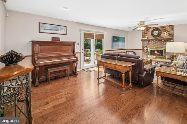 living area featuring a ceiling fan, a brick fireplace, and hardwood / wood-style flooring