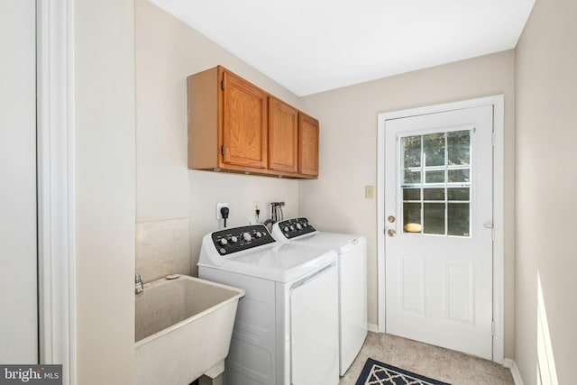 clothes washing area with washing machine and clothes dryer, baseboards, a sink, and cabinet space