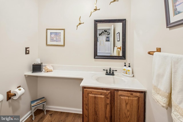 bathroom with vanity, baseboards, wood finished floors, and toilet