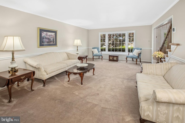 carpeted living room featuring crown molding, baseboards, and stairway