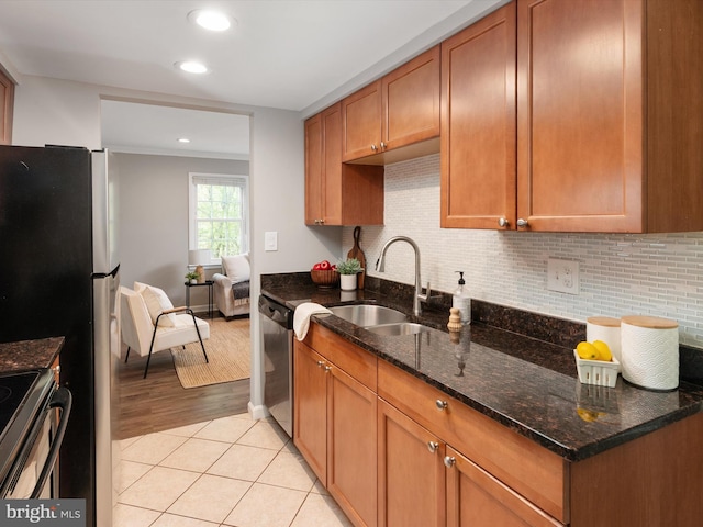 kitchen featuring appliances with stainless steel finishes, dark stone counters, decorative backsplash, and a sink