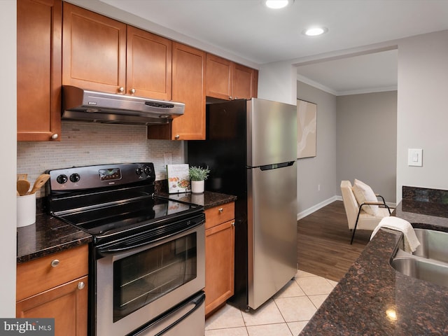 kitchen featuring under cabinet range hood, appliances with stainless steel finishes, backsplash, light tile patterned flooring, and crown molding