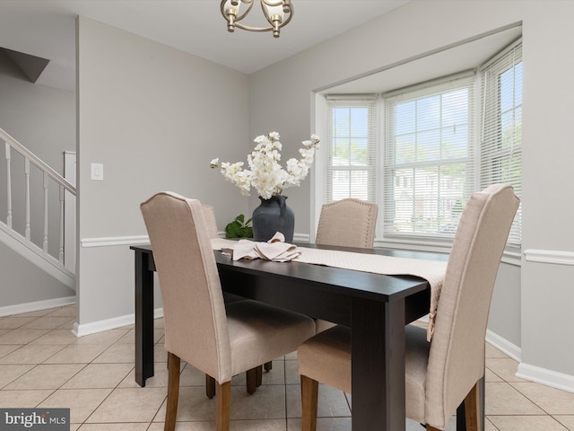 dining area with light tile patterned flooring, baseboards, a notable chandelier, and stairs