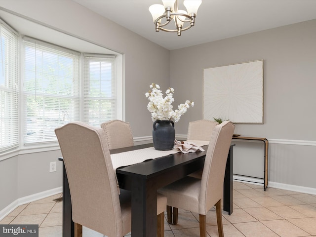 dining area with light tile patterned floors, a notable chandelier, and baseboards