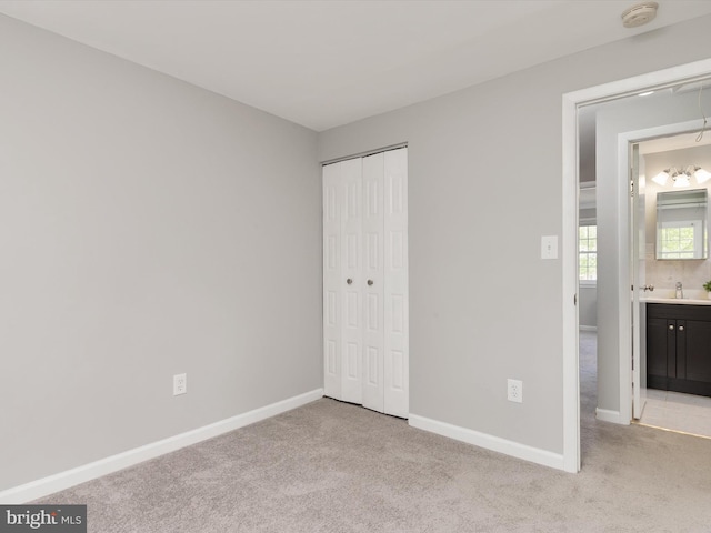 unfurnished bedroom featuring a sink, a closet, carpet flooring, and baseboards
