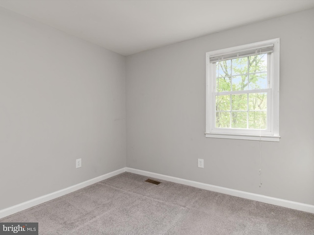 carpeted spare room with visible vents and baseboards