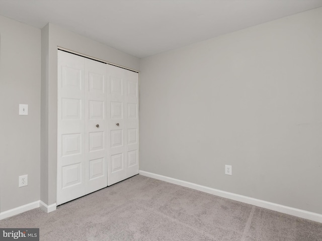 unfurnished bedroom featuring a closet, carpet floors, and baseboards