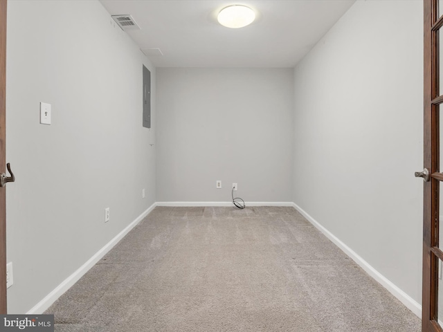 carpeted spare room with visible vents, electric panel, and baseboards