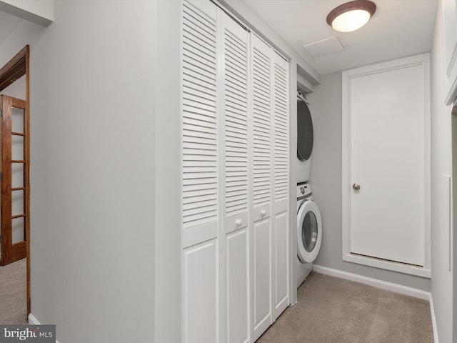 laundry room featuring stacked washer / dryer, baseboards, laundry area, and light carpet