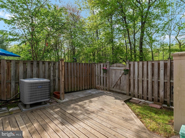wooden deck with a gate, cooling unit, and a fenced backyard