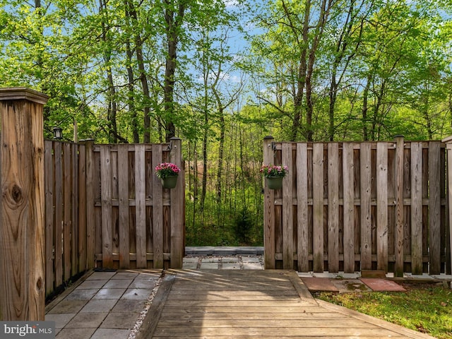 view of gate with fence and a wooden deck