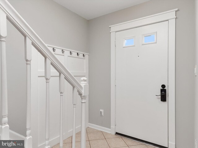 foyer with light tile patterned flooring, stairway, and baseboards