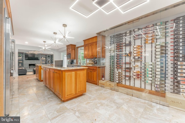 kitchen featuring open floor plan, appliances with stainless steel finishes, a chandelier, an island with sink, and pendant lighting