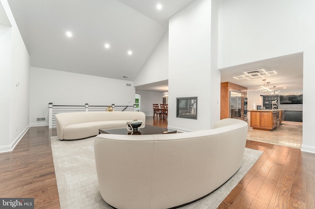 living area featuring light wood-style flooring, high vaulted ceiling, recessed lighting, and baseboards
