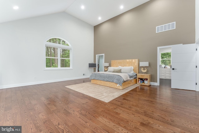 bedroom with high vaulted ceiling, wood finished floors, and baseboards