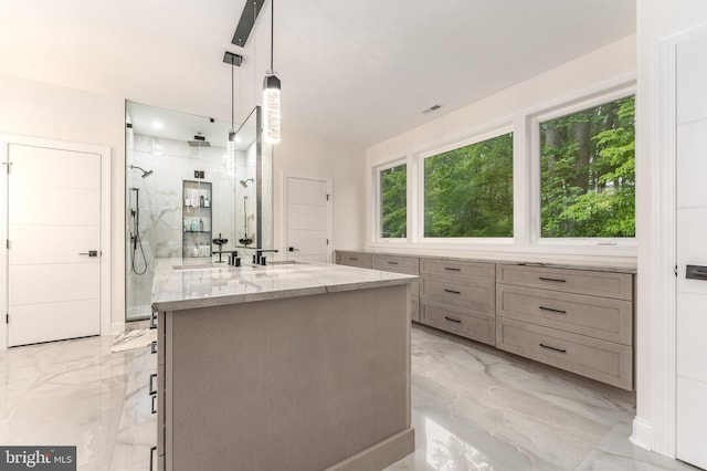 bathroom with marble tiled floors, a marble finish shower, and vanity