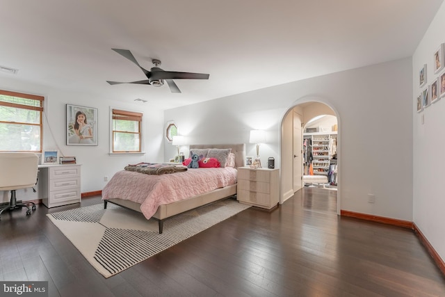 bedroom with arched walkways, dark wood-type flooring, an office area, and baseboards