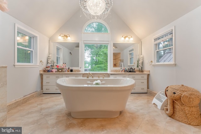 bathroom featuring a soaking tub, vanity, a chandelier, tile patterned flooring, and high vaulted ceiling