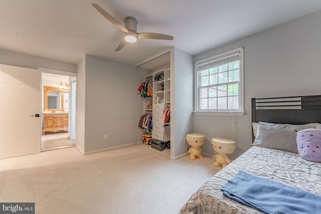 carpeted bedroom with a spacious closet, a closet, ceiling fan, ensuite bath, and baseboards