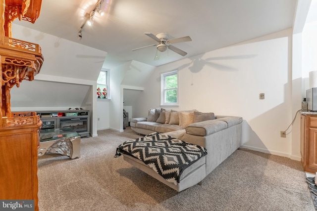 living room with a ceiling fan, light carpet, lofted ceiling, baseboards, and rail lighting
