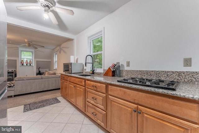 kitchen featuring black gas stovetop, ceiling fan, light tile patterned floors, a sink, and healthy amount of natural light