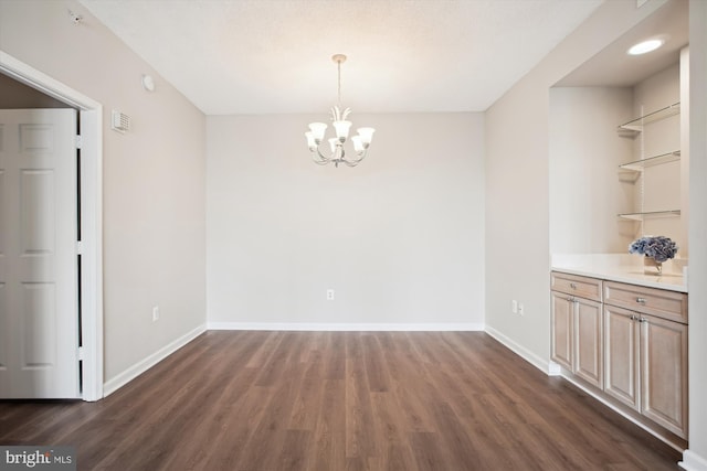 unfurnished dining area with a chandelier, dark wood finished floors, visible vents, and baseboards