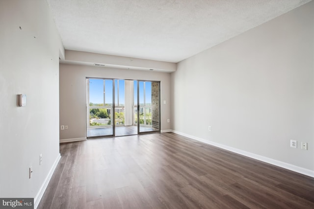 spare room featuring baseboards, wood finished floors, and a textured ceiling