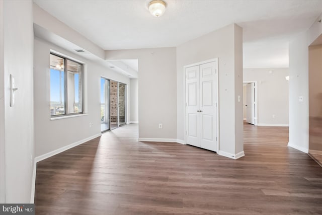unfurnished room with wood finished floors, visible vents, and baseboards