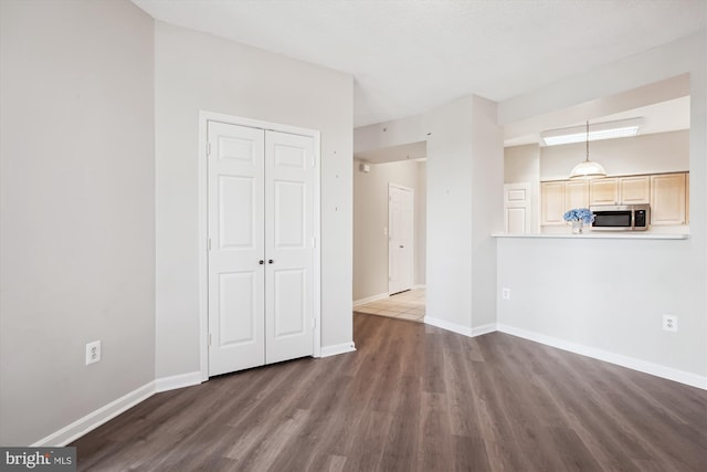 unfurnished living room with baseboards and wood finished floors