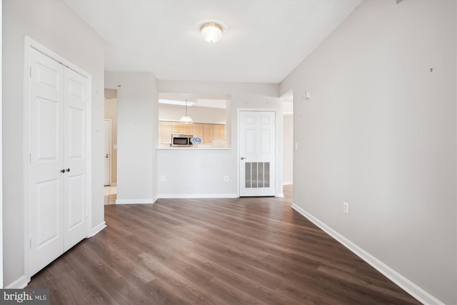 unfurnished living room featuring baseboards, dark wood-style flooring, and visible vents