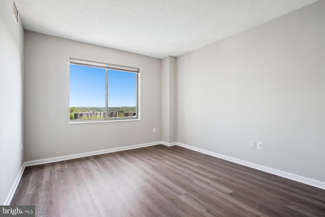 spare room with dark wood finished floors, baseboards, and visible vents