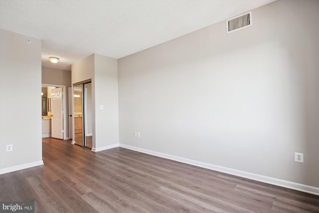 empty room featuring baseboards, dark wood-type flooring, and visible vents