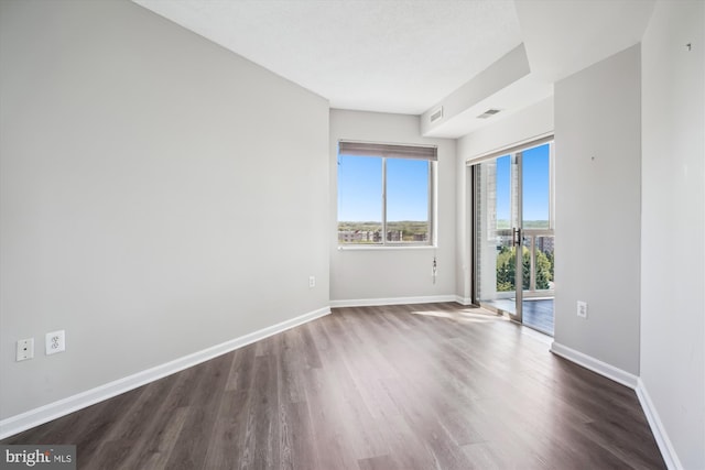 spare room featuring dark wood finished floors, visible vents, and baseboards