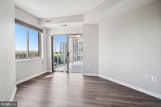 spare room featuring baseboards, visible vents, and dark wood-style floors