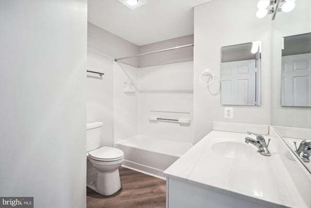 bathroom with wood finished floors, toilet, vanity, and bathtub / shower combination