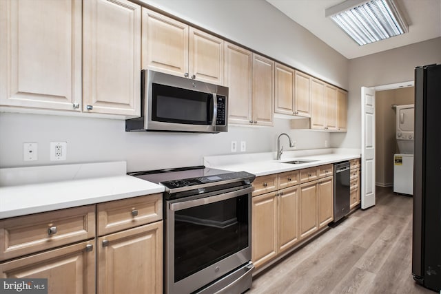 kitchen featuring light brown cabinets, appliances with stainless steel finishes, a sink, and light wood finished floors