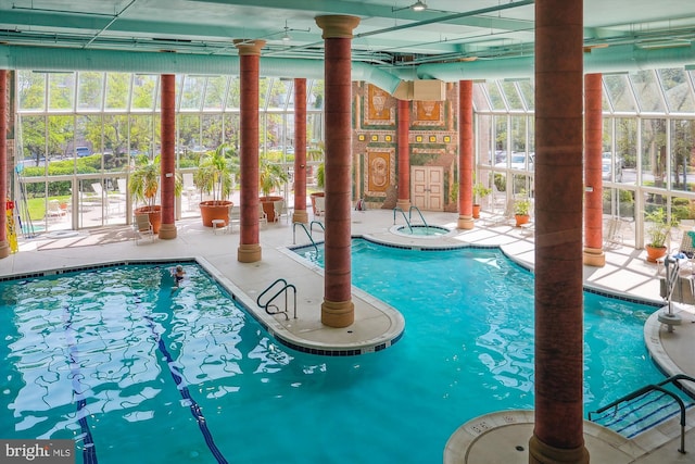 pool with an indoor in ground hot tub and a patio