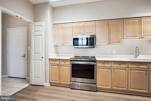 kitchen featuring light brown cabinets, appliances with stainless steel finishes, a sink, and light countertops