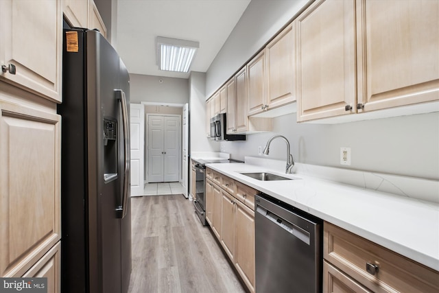kitchen with stainless steel appliances, a sink, light wood-type flooring, light brown cabinets, and light countertops