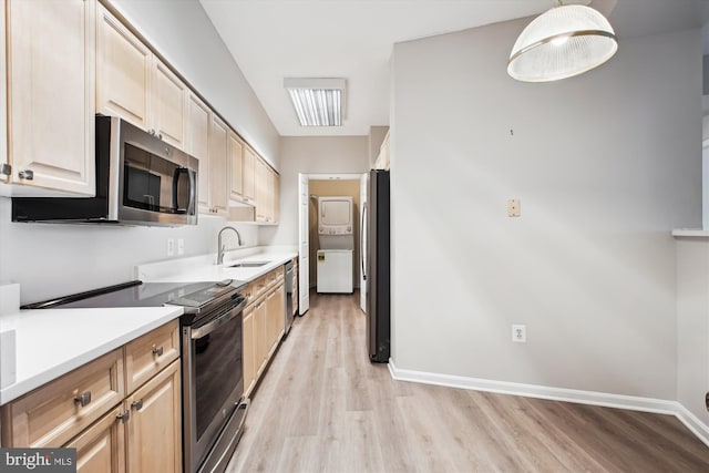 kitchen featuring a sink, light brown cabinetry, stacked washer / drying machine, stainless steel appliances, and light wood-style flooring