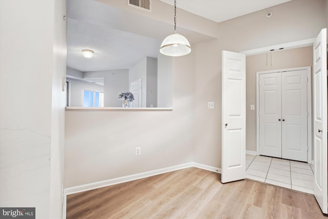 unfurnished dining area featuring baseboards, wood finished floors, and visible vents