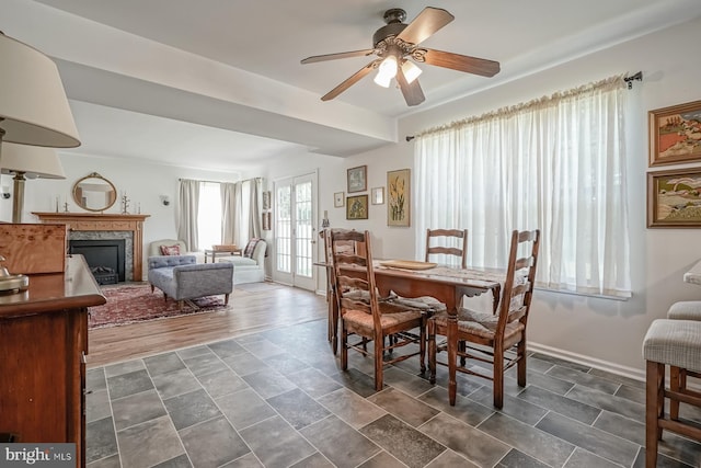 dining space featuring baseboards, ceiling fan, and a fireplace